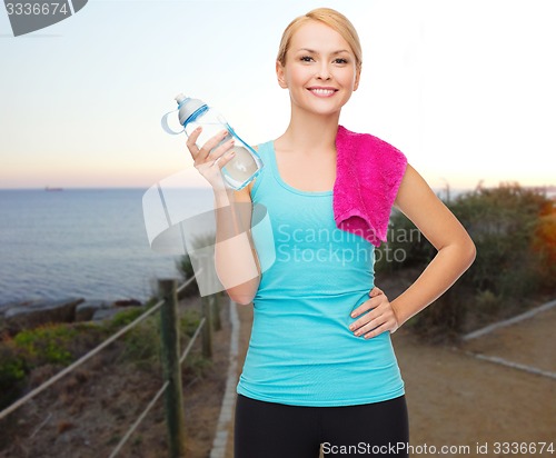 Image of happy woman with water bottle and towel outdoors