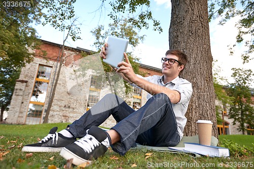 Image of happy teenage boy with tablet pc taking selfie