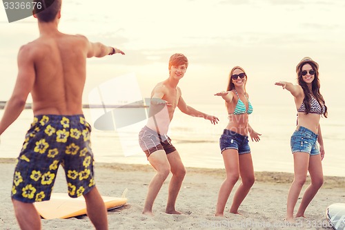 Image of smiling friends in sunglasses with surfs on beach