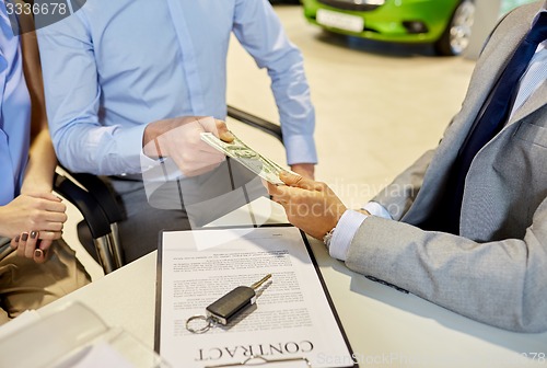 Image of customers giving money to car dealer in auto salon