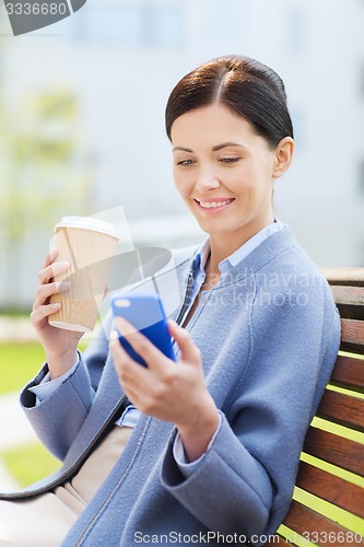 Image of smiling woman with coffee and smartphone