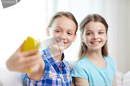 Image of happy girls with smartphone taking selfie at home