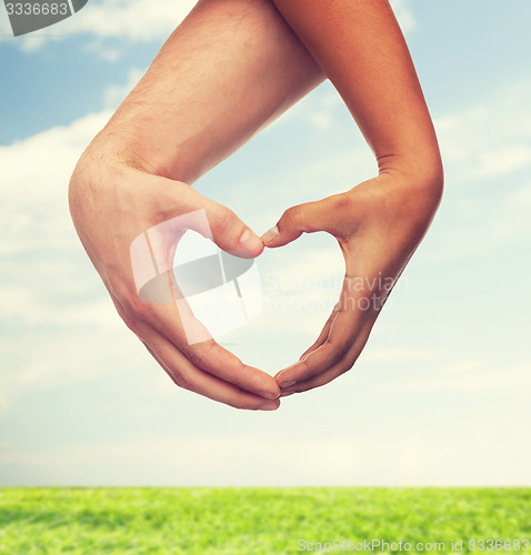 Image of woman and man hands showing heart shape