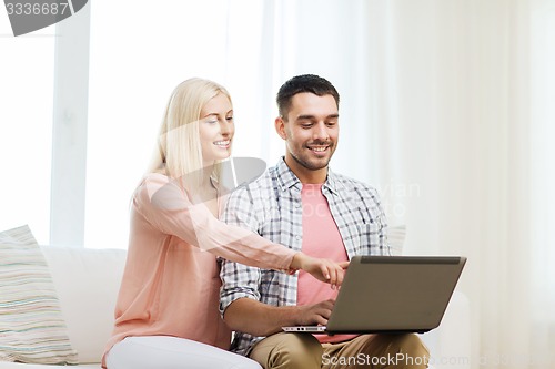 Image of smiling happy couple with laptop computer at home