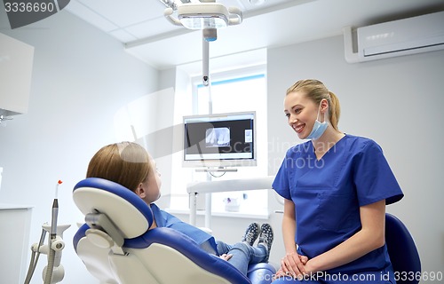 Image of happy female dentist with patient girl at clinic