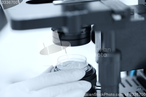 Image of close up of hand with microscope and powder sample