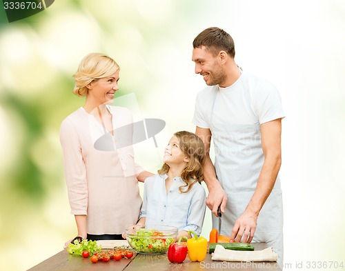 Image of happy family cooking vegetable salad for dinner