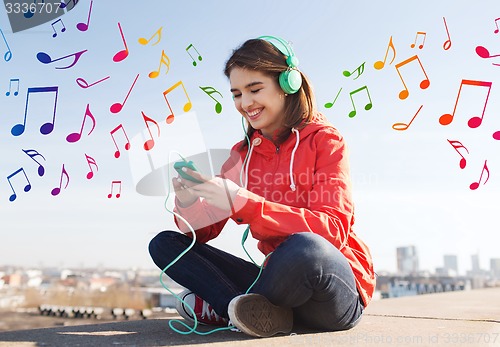 Image of happy young woman with smartphone and headphones