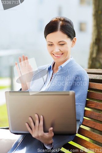 Image of smiling business woman with laptop in city