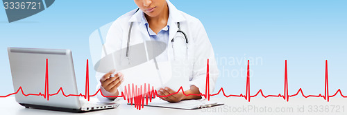 Image of female doctor with laptop pc looking at paper