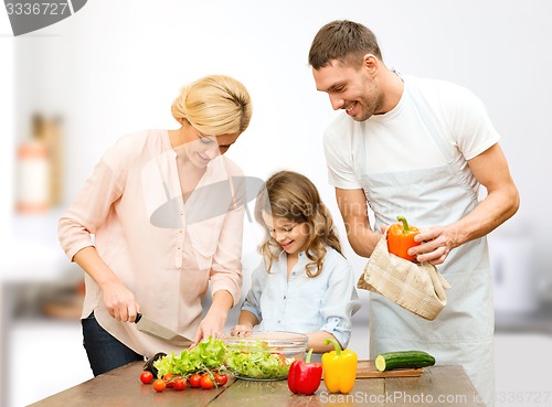 Image of happy family cooking vegetable salad for dinner