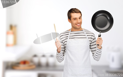 Image of happy man or cook in apron with pan and spoon