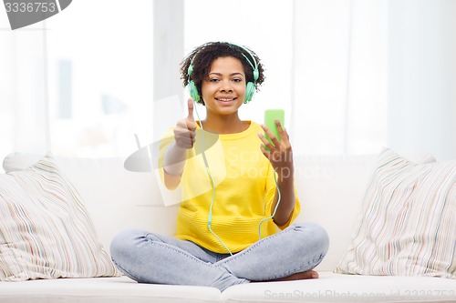 Image of happy african woman with smartphone and headphones