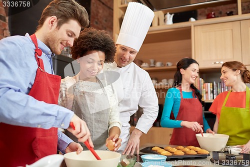 Image of happy friends and chef cook baking in kitchen