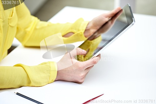 Image of close up of female hands with tablet pc at table