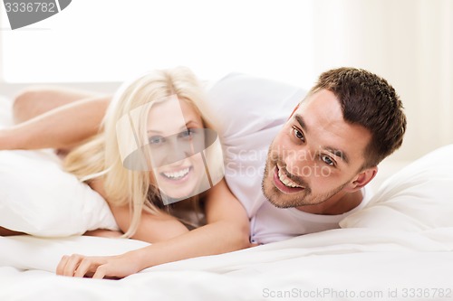 Image of happy couple lying in bed at home