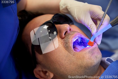 Image of close up of male patient with dental curing light