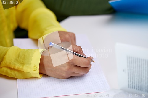 Image of close up of female hands writing to notebook