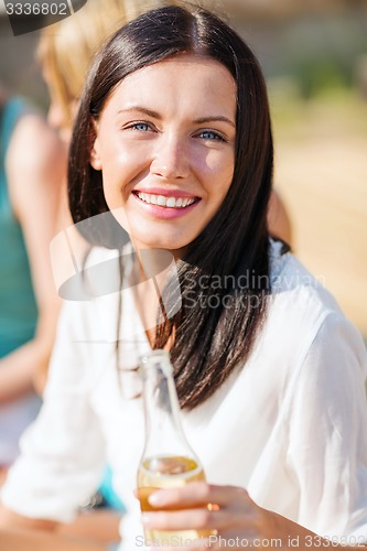 Image of girl with drink and friends on the beach