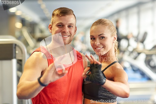 Image of smiling man and woman showing ok hand sign in gym