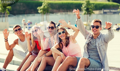 Image of group of laughing friends sitting on city square