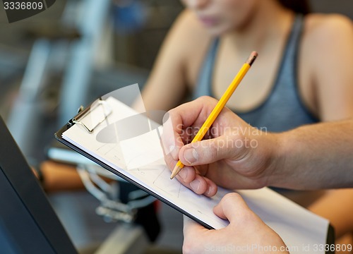 Image of close up of trainer hands with clipboard in gym