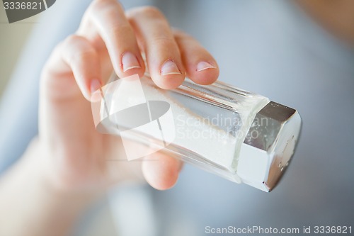 Image of close up of hand holding white salt cellar