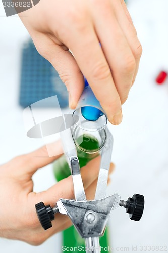 Image of close up of scientist filling test tubes in lab