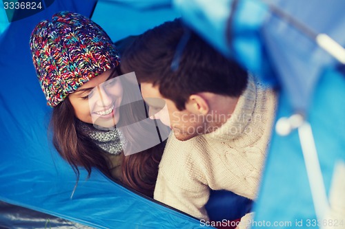 Image of smiling couple of tourists looking out from tent