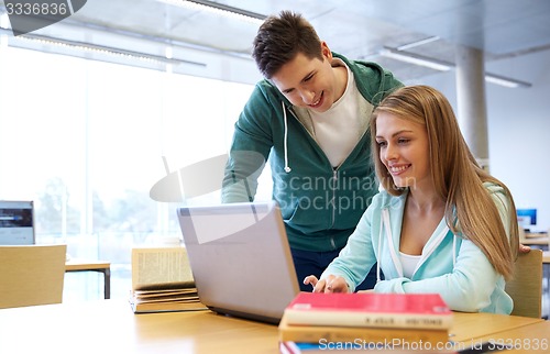 Image of happy students with laptop in library