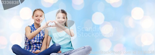 Image of happy little girls showing heart shape hand sign