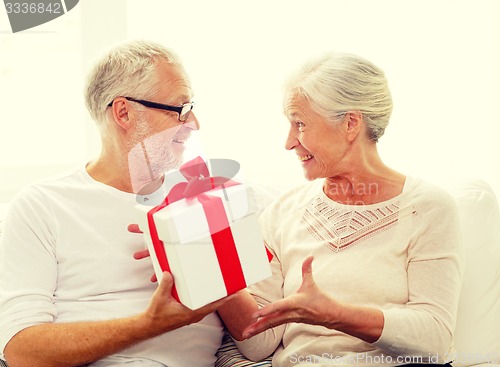 Image of happy senior couple with gift box at home