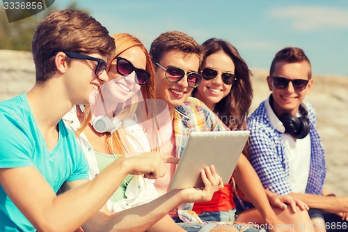 Image of group of smiling friends with tablet pc outdoors