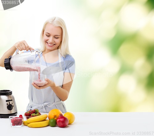 Image of smiling woman with blender and fruit milk shake