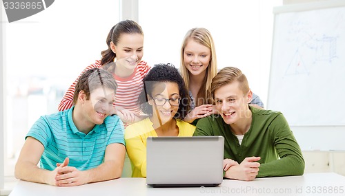 Image of smiling students looking at laptop at school