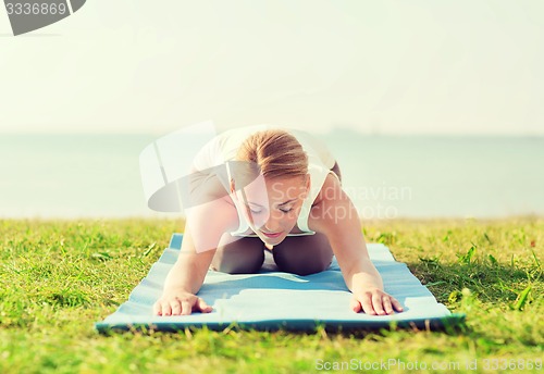 Image of young woman making yoga exercises outdoors
