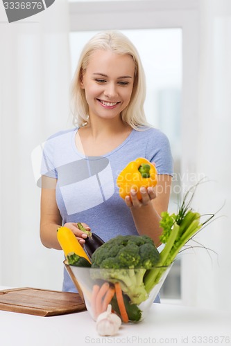 Image of smiling young woman cooking vegetables at home