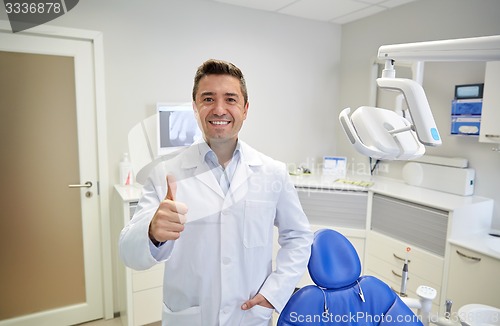 Image of happy male dentist showing thumbs up at clinic