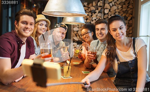 Image of friends with smartphone on selfie stick at bar