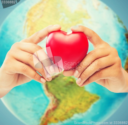 Image of woman hands holding red heart over earth globe