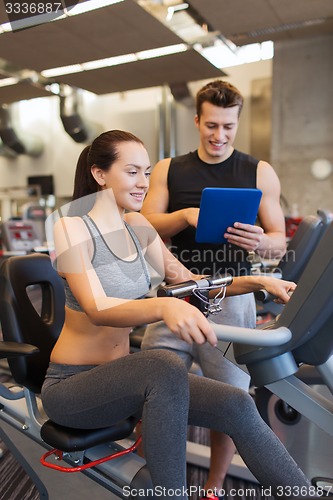 Image of happy woman with trainer on exercise bike in gym