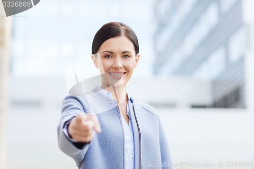 Image of young smiling businesswoman over office building