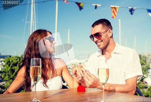 Image of smiling couple with champagne and gift at cafe