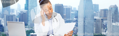 Image of female doctor with laptop reading medical report