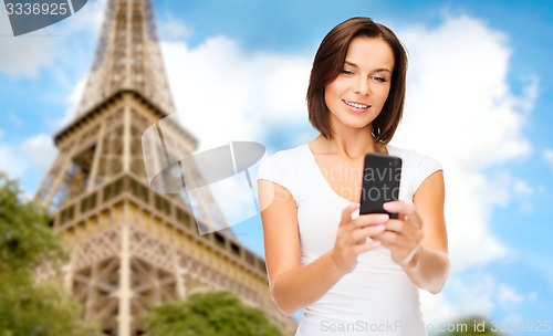 Image of woman with smartphone over eiffel tower