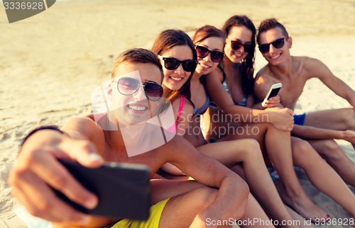 Image of friends with smartphones on beach