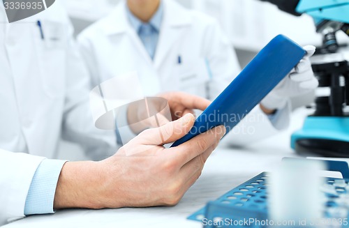 Image of close up of scientists hands with tablet pc in lab