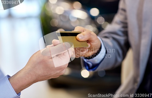 Image of customer giving credit card to car dealer in salon