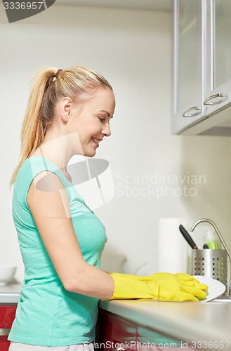 Image of happy woman washing dishes at home kitchen