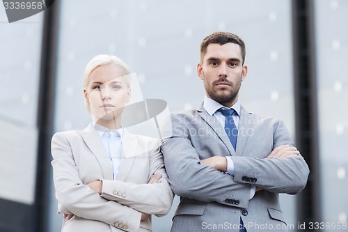 Image of serious businessmen standing over office building